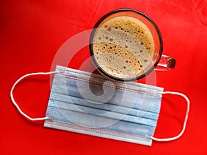 Flat lay shot of Teh tarik, the famous Malaysian tea and sweetened, onÃÂ red background with face mask.ÃÂ  photo